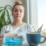 P of a young adult sitting by a bright apartment window, soft daylight illuminating their thoughtful face